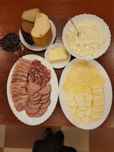 una mesa con platos de diferentes tipos de carne y queso en Jono Pauliaus II piligrimu namai en Raseiniai
