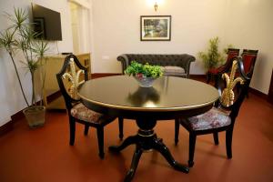 Heritage Home in Central Kolkata في كولْكاتا: طاولة عليها كراسي و إناء من الزهور