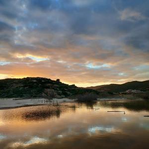 a body of water with a sunset in the background at La Rosa dei Venti B&B in Chia