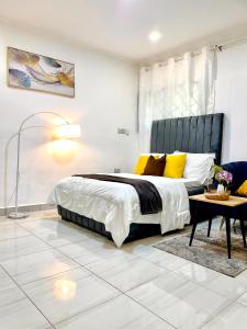 a bedroom with a bed with yellow pillows and a table at Cozy Studio Apartment in Dar es Salaam