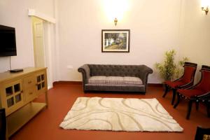 Heritage Home in Central Kolkata في كولْكاتا: غرفة معيشة بها أريكة وتلفزيون