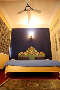 a blue bedroom with a bed with a ceiling fan at Heritage Home in Central Kolkata in Kolkata