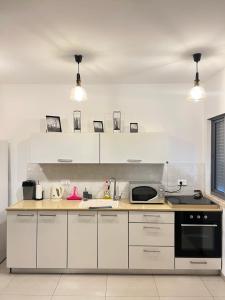 uma cozinha com armários brancos e um forno com placa de fogão em דירת גן מדרך עוז Garden Apartment em Midrakh ‘Oz