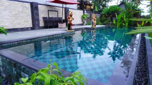 a swimming pool with a blue with an umbrella at Royani Villa in Sukawati