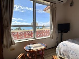a bedroom with a window and a bed and a desk at ビーチサイドペンションみーばる in Nanjo