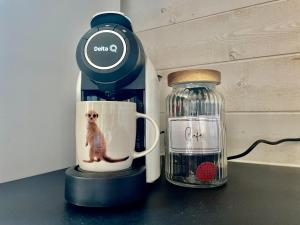 Una cafetera con una taza de café con un perro. en Le petit bois - parking privé, en Éveux