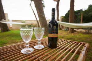 a bottle of wine and two wine glasses on a table at House on the sea garden in Marsala