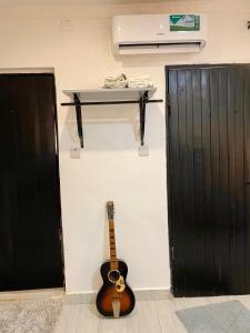 a guitar hanging on a wall next to a door at Cozy Studio Apartment in Dar es Salaam