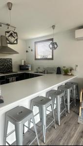 a kitchen with a white counter and stools in it at OwLHouse on Island in Cowes