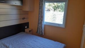 un dormitorio con una cama y una ventana en Mobil home sur Carnac, en Carnac 5 fotos más