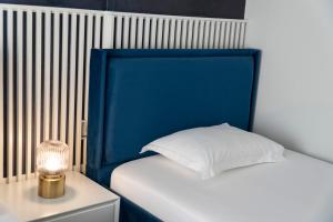 a bed with a blue headboard next to a table with a lamp at Oyster Apartments in Sarandë