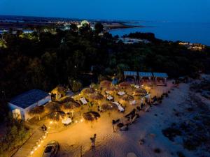 una vista aerea di una spiaggia con ombrelloni di notte di Hotel Aria di Mare a Marina di Ragusa