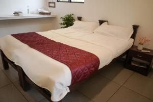 1 dormitorio con 1 cama grande con sábanas blancas y manta roja en Marari Bobans villa, en Mararikulam
