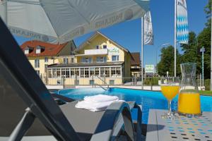 a table with an umbrella and a glass of orange juice at "NEU" Apartments-Hotel Huberhof Allershausen in Allershausen