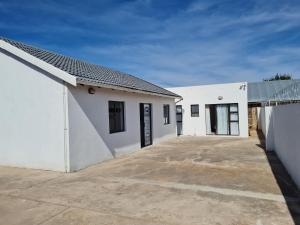 a white building with a parking lot in front of it at Mews Road Self-Catering in Queenstown