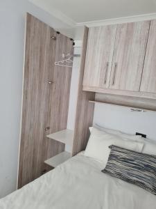 a bedroom with a white bed and wooden cabinets at Mews Road Self-Catering in Queenstown