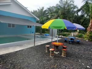 a table with a colorful umbrella next to a pool at AA Burger Homestay for Musliim Only in Banting