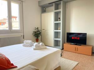 um quarto com uma cama, uma televisão e toalhas em Spazioso Apt vicino Stazione - Posto Auto em Treviso
