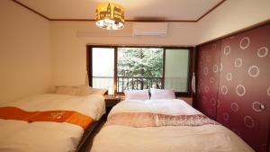 two beds in a room with a window at Open-air bath/11 mins walk from Hakone Yumoto Sta. in Hakone