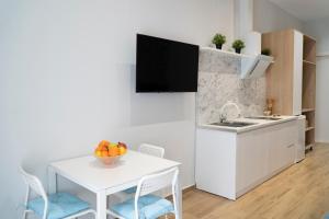 a kitchen with a white table and a white table and chairs at Oyster Apartments in Sarandë