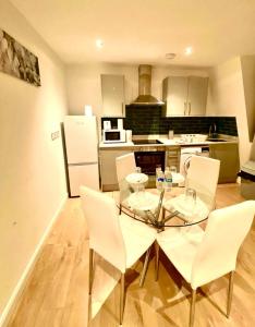 a kitchen with a glass table and white chairs at One Bedroom Apartment in Ealing Broadway London in Ealing