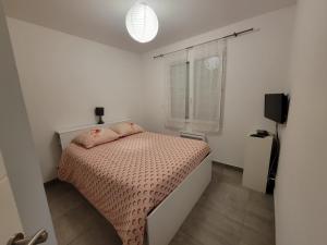 a small bedroom with a bed with pink sheets and a window at Villas Floryanne - bassin arcachon in Audenge