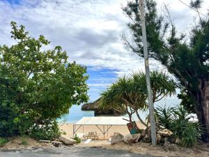 a picnic table on a beach with a view of the ocean at ビーチサイドペンションみーばる in Nanjo