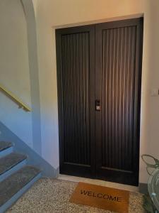 una porta nera con un tappetino di benvenuto davanti di YOLE Affittacamere a Empoli