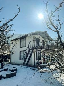 a house covered in snow with the sun behind it at MANDAP COTTAGE & CAFE in Nagar