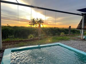 uma piscina num quintal com um pôr-do-sol ao fundo em Chalet Tepi Sungai em Pokok Sena