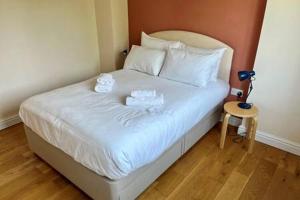 Una cama con sábanas blancas y dos toallas. en Charming 1 bed super central Terraced House, en Cambridge
