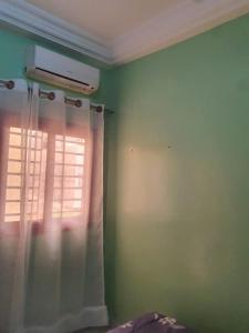 een slaapkamer met een raam met een gordijn bij Residence Hadja 03 in Dakar