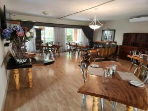 una sala da pranzo con tavoli e sedie in legno di The Green Lizard Guesthouse a Nelspruit