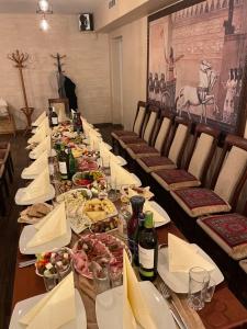 Hotel Jerevan في دروسكينينكاي: طاولة طويلة مع أطباق من الطعام وزجاجات من النبيذ