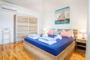 een slaapkamer met een groot blauw bed met kussens bij Apartment Tara in Njivice