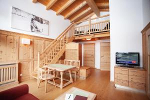 a living room with a wooden staircase and a table at Naturresort Senningerhof in Bramberg am Wildkogel