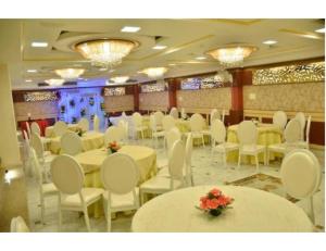 a banquet hall with white tables and white chairs at Hotel Galaxy Grand, Lucknow in Lucknow
