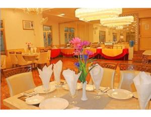 a table with plates and vases with flowers on it at Hotel Galaxy Grand, Lucknow in Lucknow