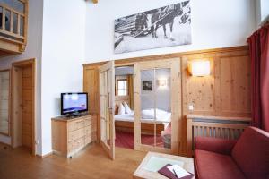 a living room with a television and a room with a bed at Naturresort Senningerhof in Bramberg am Wildkogel