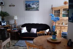 ein Wohnzimmer mit einer schwarzen Couch und einem Tisch in der Unterkunft Maison Familiale à la Montagne in Soulom + 8 Fotos