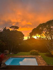 a swimming pool with a sunset in the background at Rose Cottage in Trafalgar