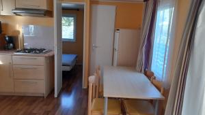 a small kitchen with a table and a room with a bed at Mobil home sur Carnac in Carnac