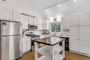 a kitchen with white cabinets and a stainless steel refrigerator at Cape Cod Retreat with Beach Access in Falmouth