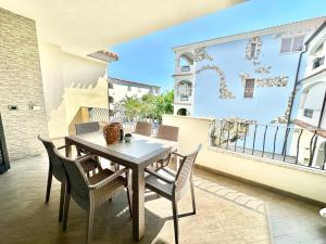 a patio with a table and chairs on a balcony at Lux Limone - Appartamenti in residence con piscina in Orosei