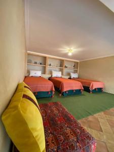 ein Zimmer mit 3 Betten und einem Sofa darin in der Unterkunft Dar diafa samira in Mirleft