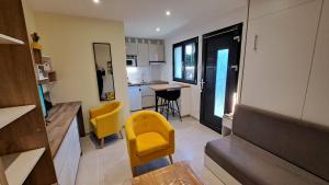 a living room with a yellow chair and a kitchen at Studio Cécilia in Aix-les-Bains