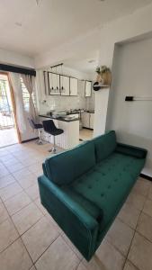 a green couch in a living room with a kitchen at Nomads Nest Fiji in Suva