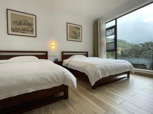 - une chambre avec 2 lits et une grande fenêtre dans l'établissement 千岛湖月下民宿, à Liyang