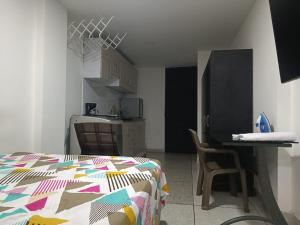 a bedroom with a bed and a table and a kitchen at Apto 101 in Cúcuta