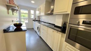 une cuisine avec des armoires blanches et un four à plaques de cuisson dans l'établissement Precioso apartamento en la playa de Jávea By El Conserje, à Jávea